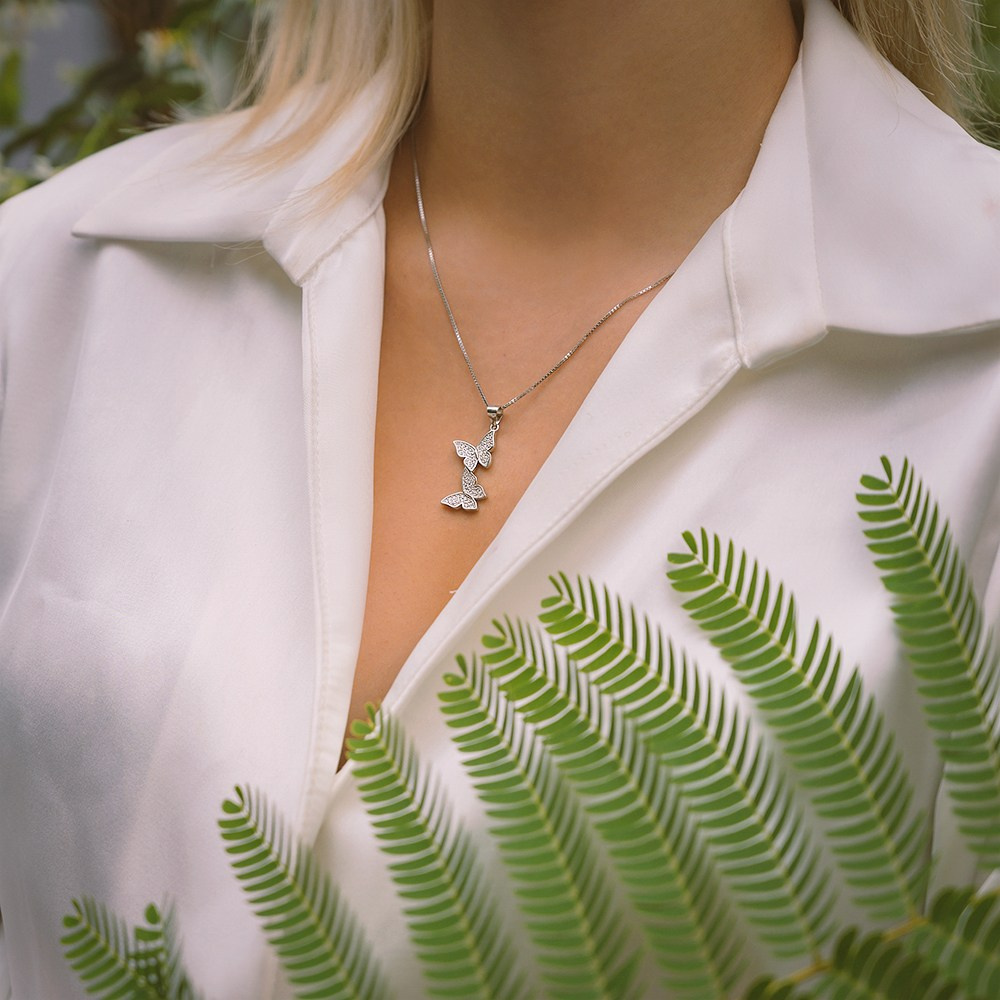 Zlatna ogrlica na devojci u beloj košulji.