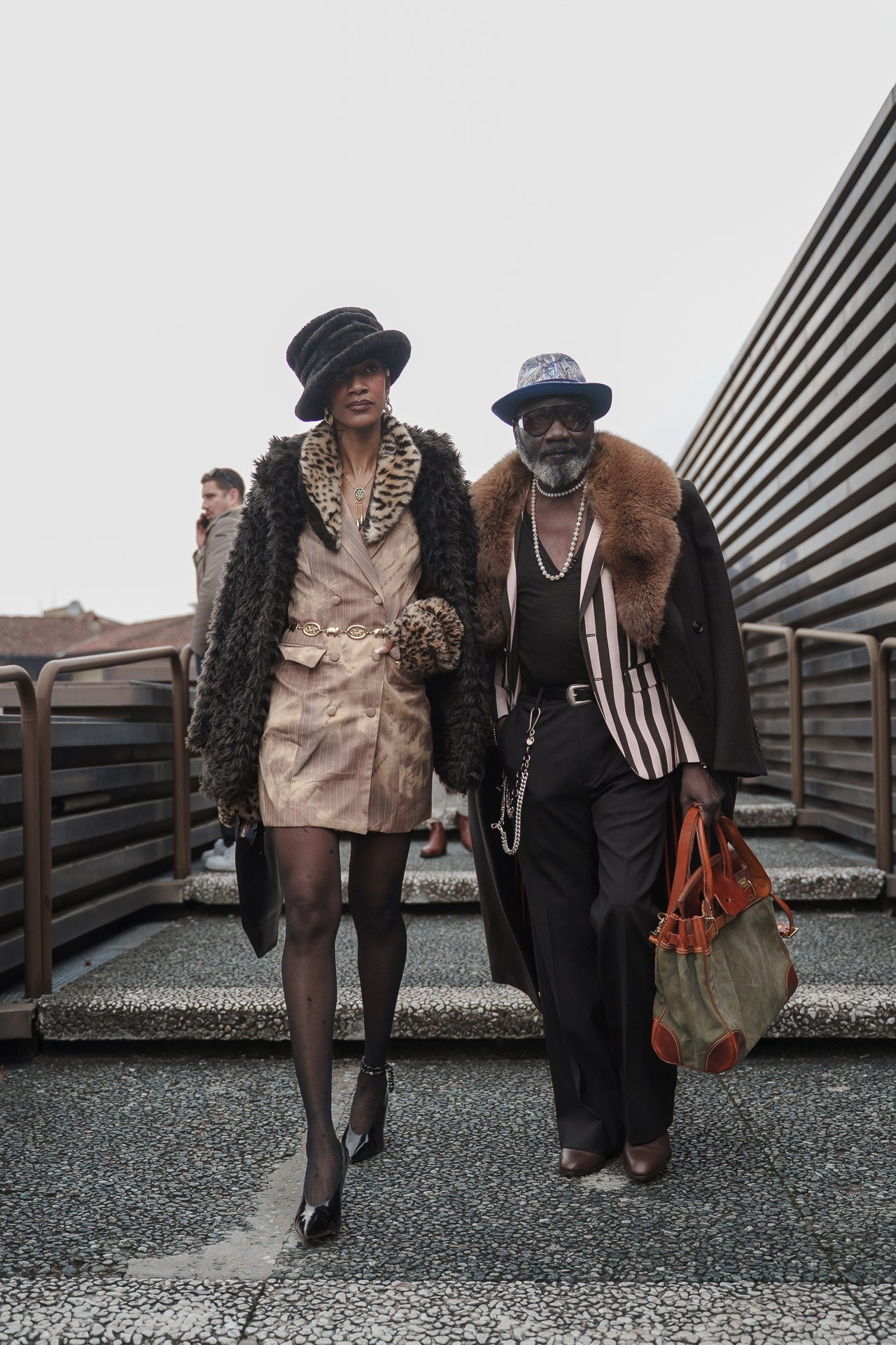 Fashionable couple in fur coats walking together at Pitti Uomo 109 Florence