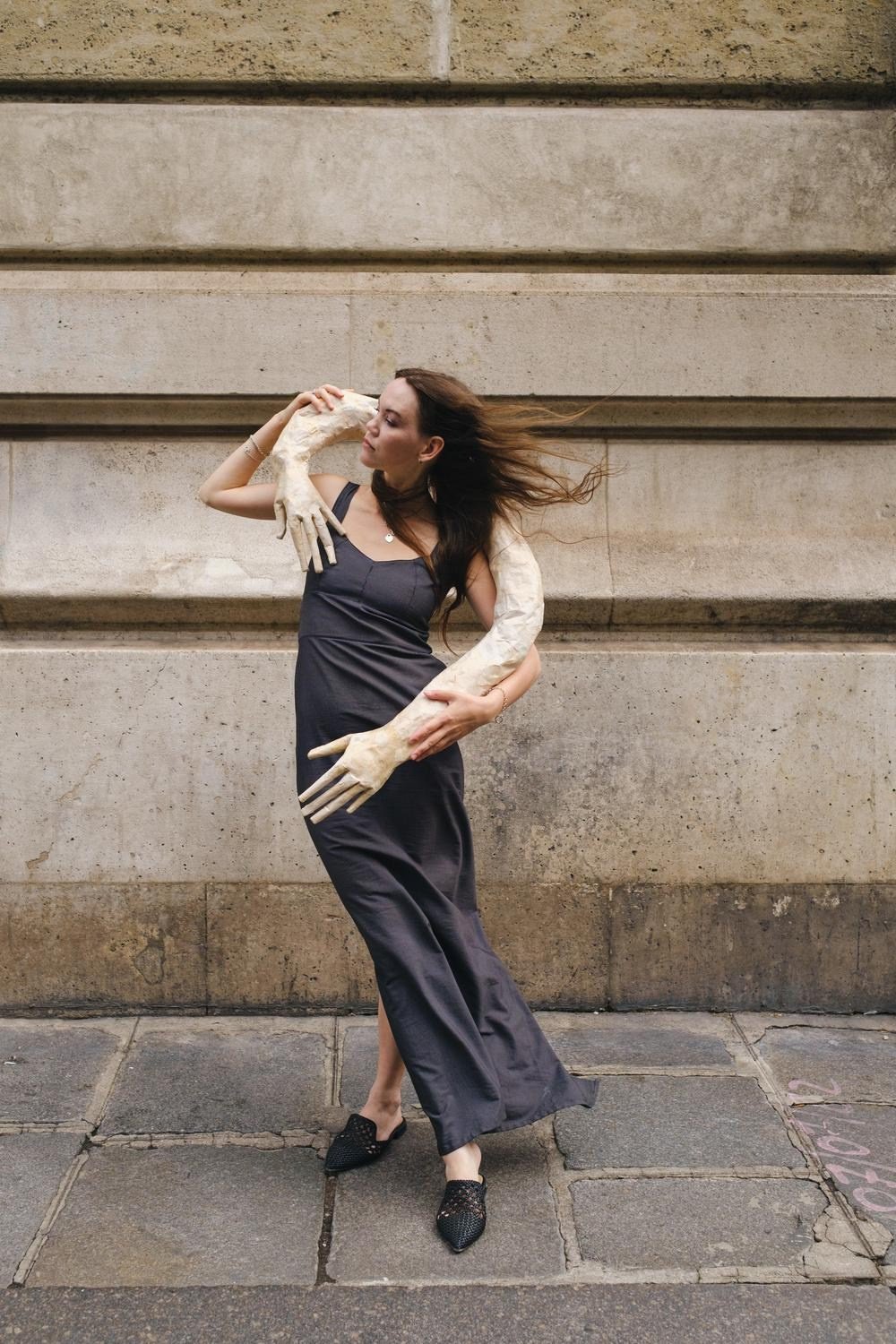 Dynamic commercial fashion walk featuring a flowing dark grey dress on a stone street