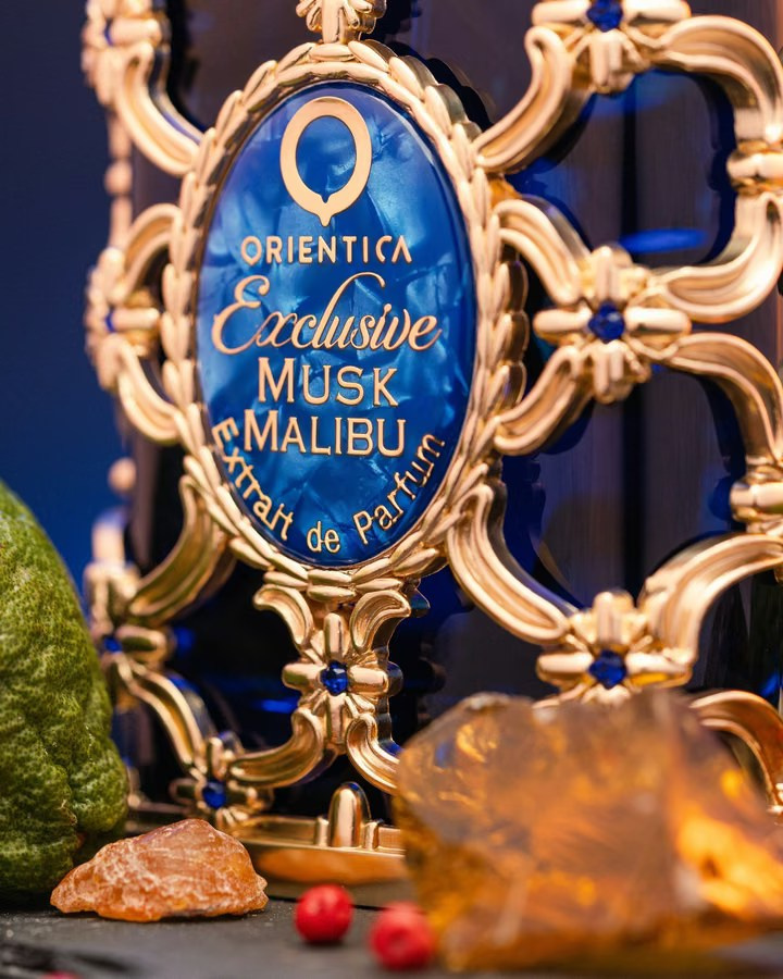 Ornate blue and gold perfume bottle surrounded by incense resin and spices