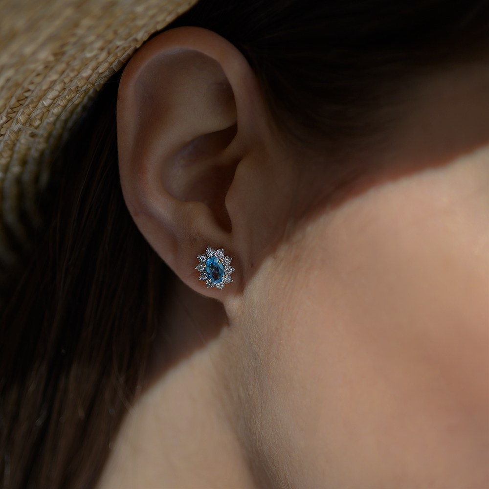 Minđuša sa plavim topazom na uhu devojke koja nosi šešir.