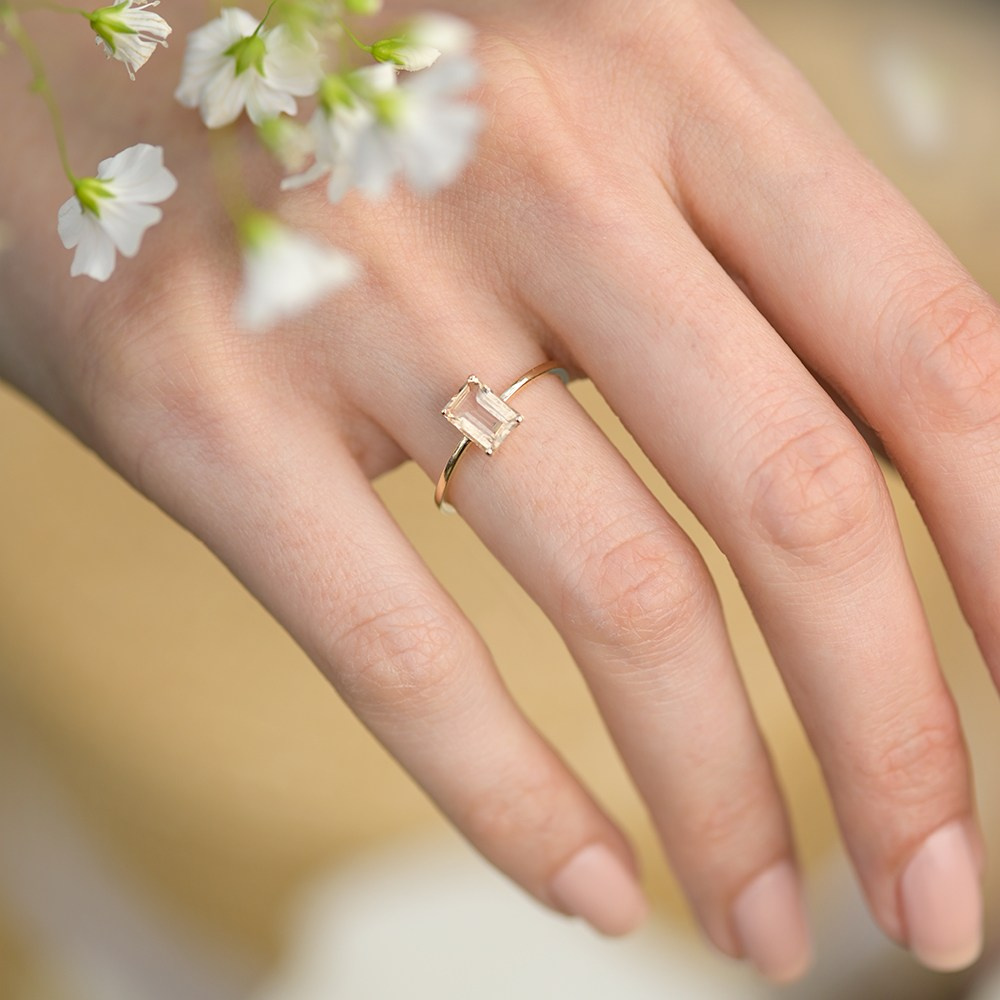 Zlatni prsten na ruci devojke sa cvetićima.