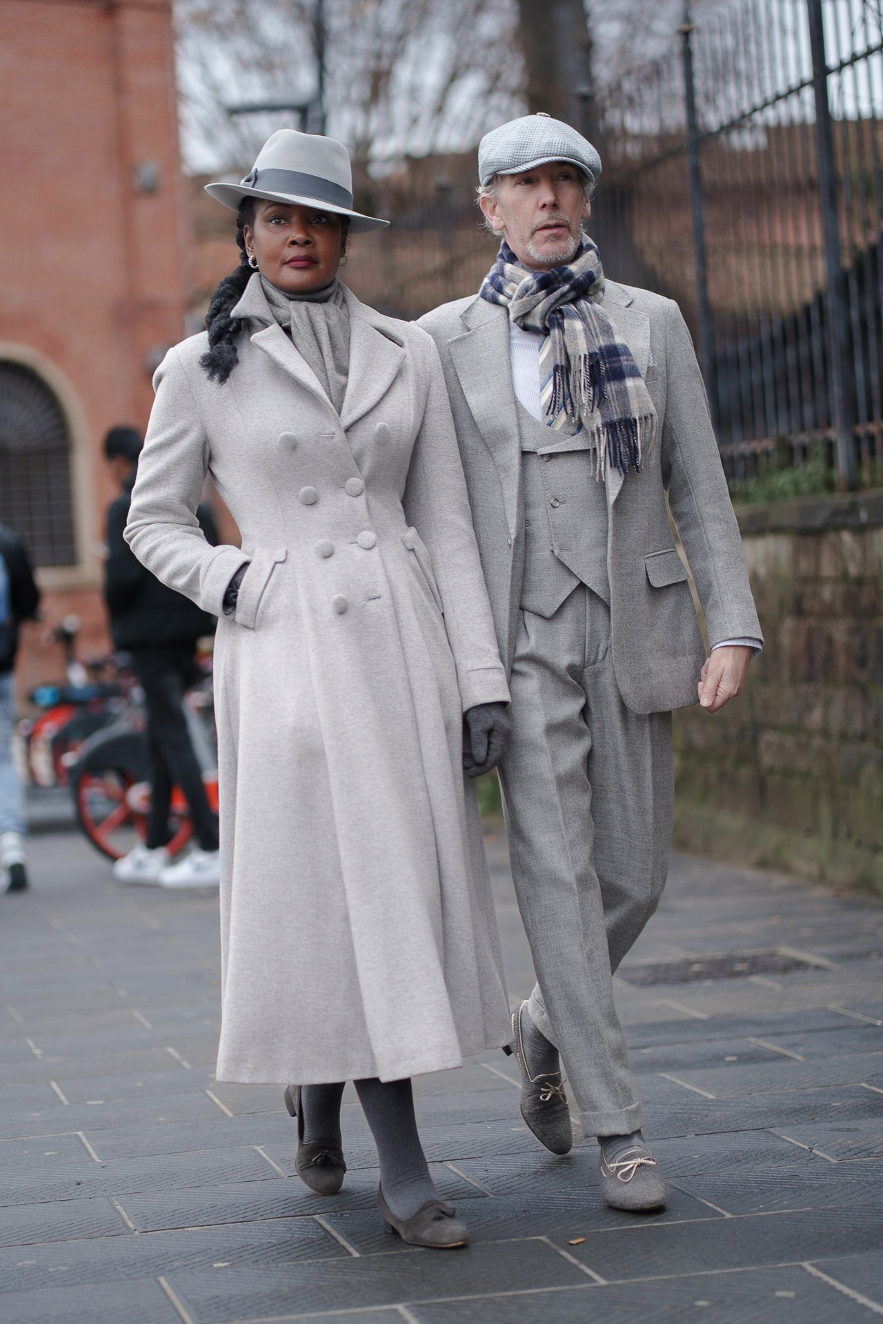 Well dressed couple in matching grey coats walking outside Pitti Uomo 109 Florence