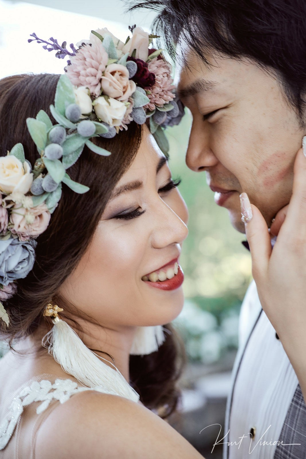 Bride caressing groom's face lipstick kiss mark close-up portrait.