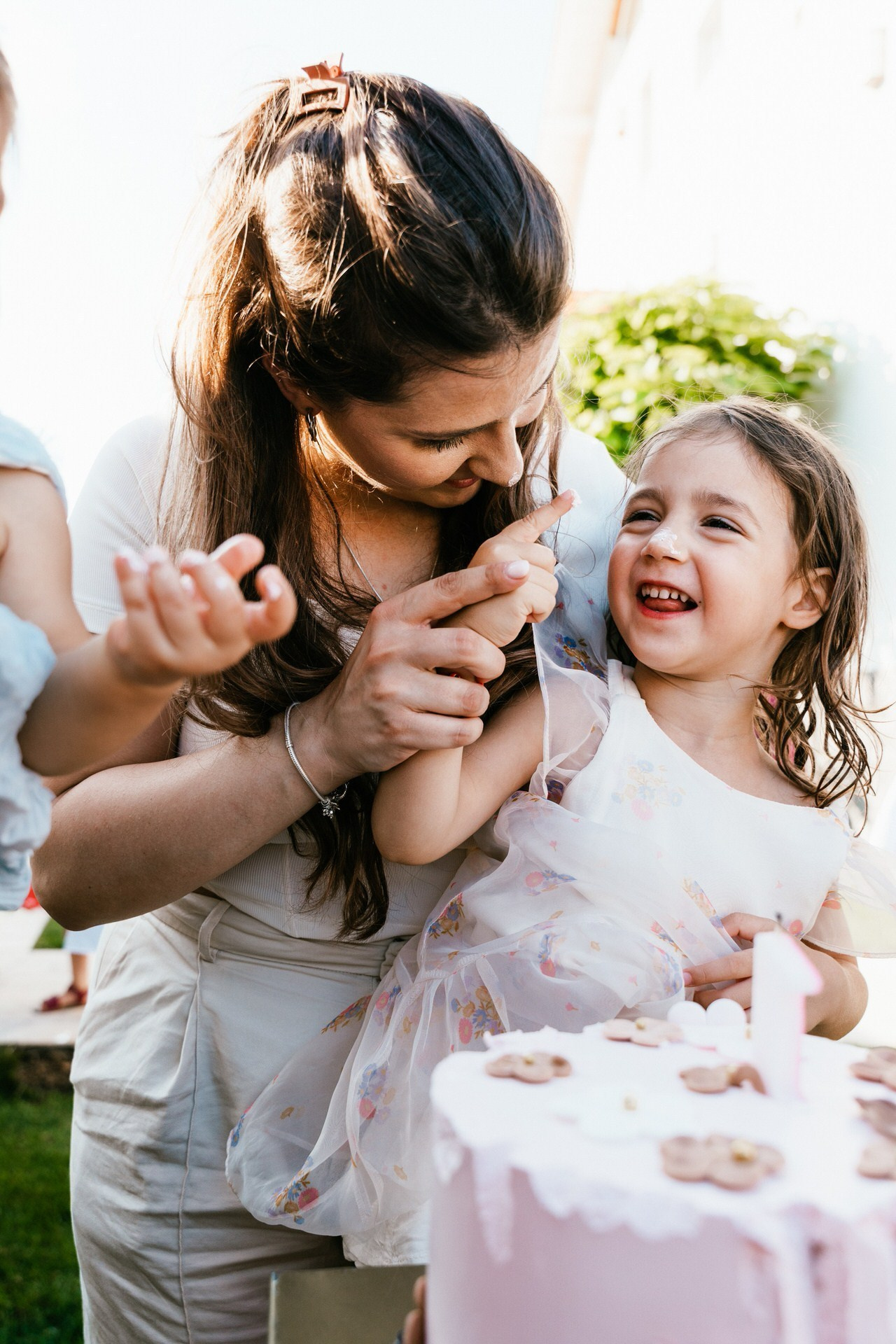 kadar nasmejana devojčica koju je mama umazala šlago sa rođendanske torte po nosu
