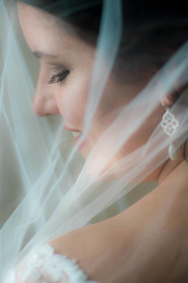 A horizontal, rear view of a smiling bride under her veil.