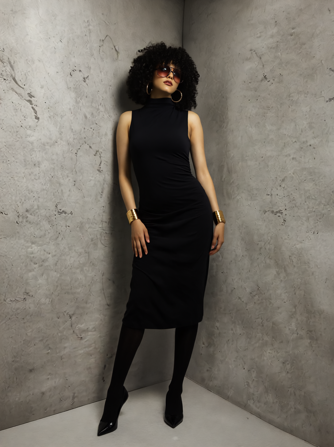 Studio portrait of a woman in a fitted black dress photographed against a grey textured wall in a refined editorial style