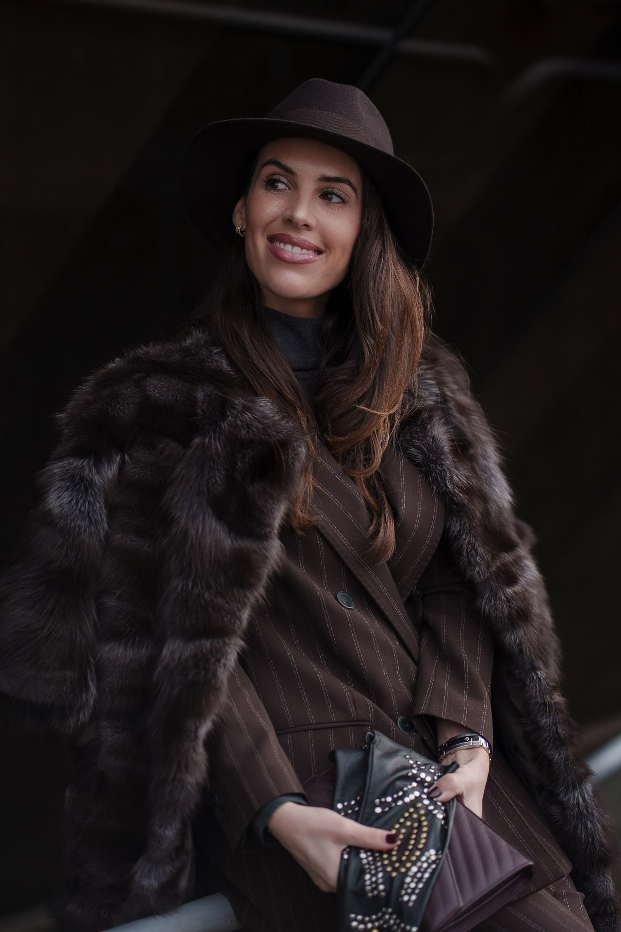 Woman in fur coat and brown outfit smiling at Pitti Uomo street style