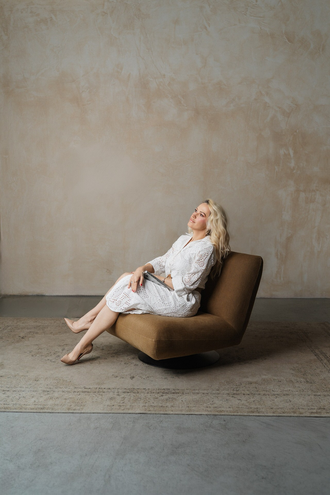 devojka sedi na fotelji u beloj haljini zamišljeno gleda u daljinu