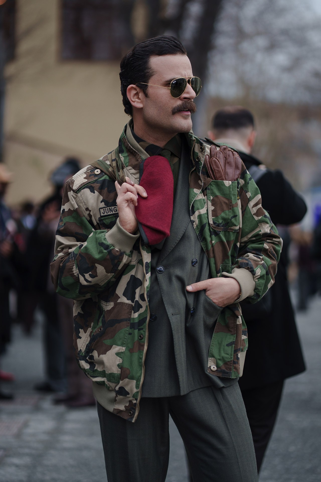Man in camouflage jacket and red gloves at Pitti Uomo 109 Florence