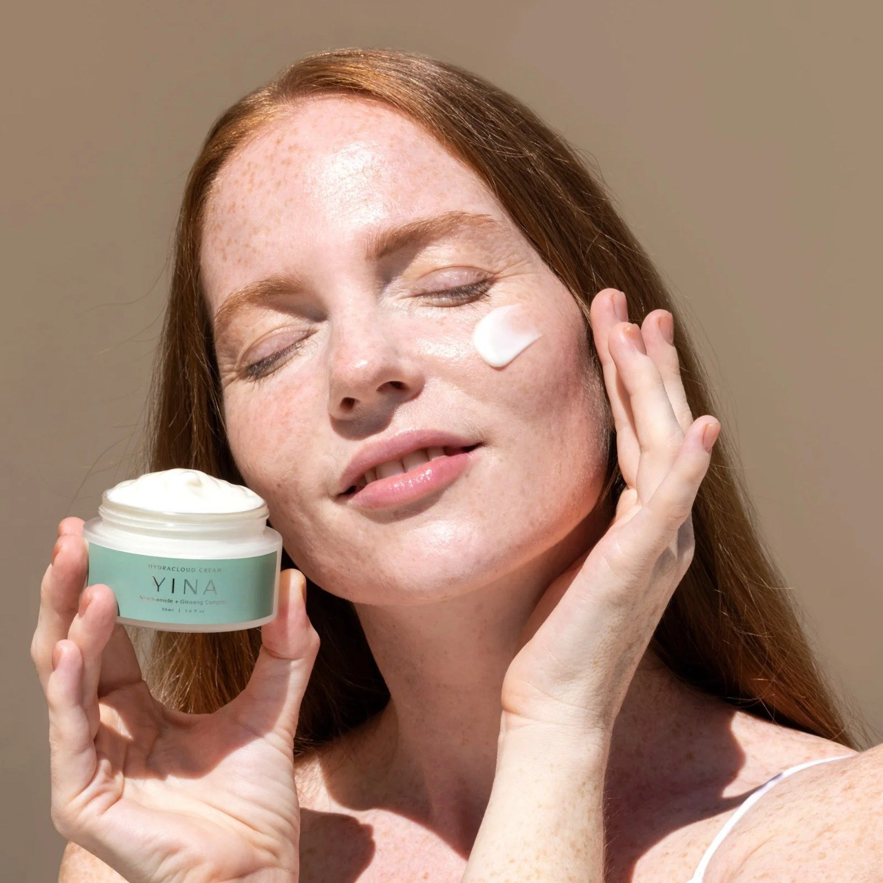 Portrait of a woman with closed eyes, emanating a sense of calm and serenity. Her hair is styled naturally, and her makeup is soft and subtle, enhancing her features without overpowering them. The lighting is gentle, creating a soothing atmosphere that highlights the model's peaceful expression.