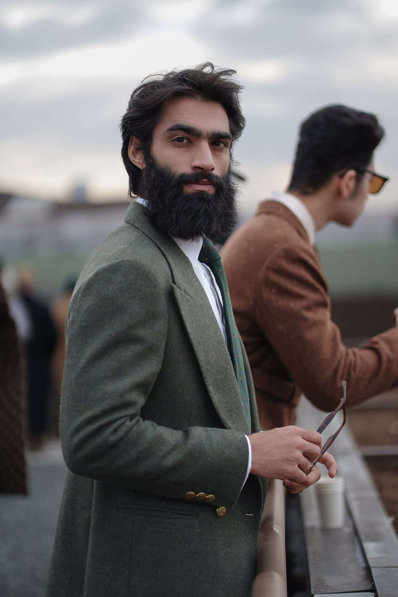 Bearded man in green suit holding glasses at Pitti Uomo Florence street style