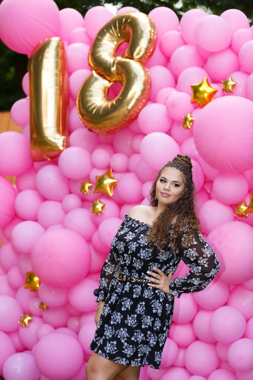 Devojka pozira ispred dekoracije sa balonima za 18. rođendan – profesionalna fotografija proslave.