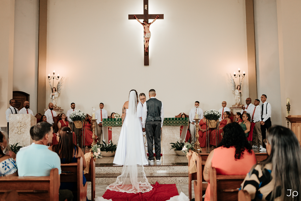Fotógrafo de Bariri registra foto dos noivos no altar de uma igreja, com padre e padrinhos ao fundo.