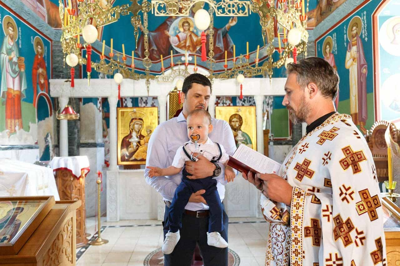 Kum drži bebu tokom obreda krštenja