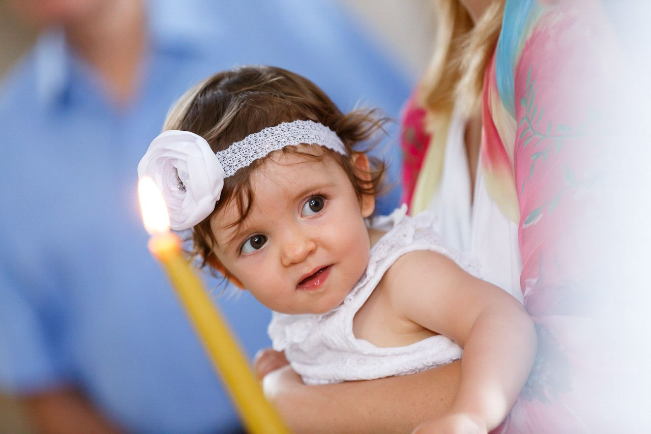 Radostan portret devojčice za vreme obreda krštenja.