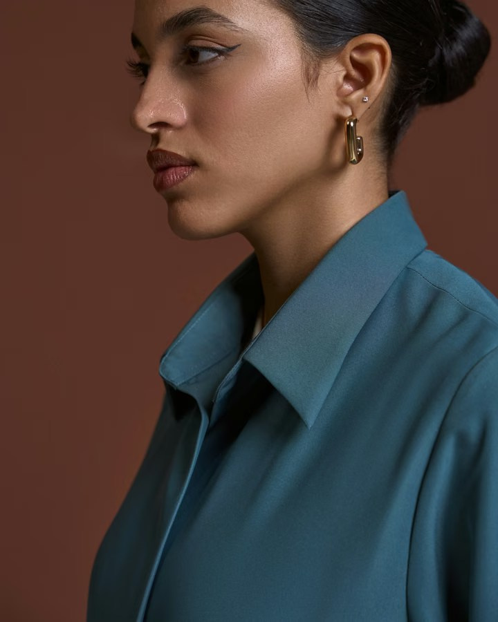 Close-up portrait of a model wearing gold earrings and a blue shirt
