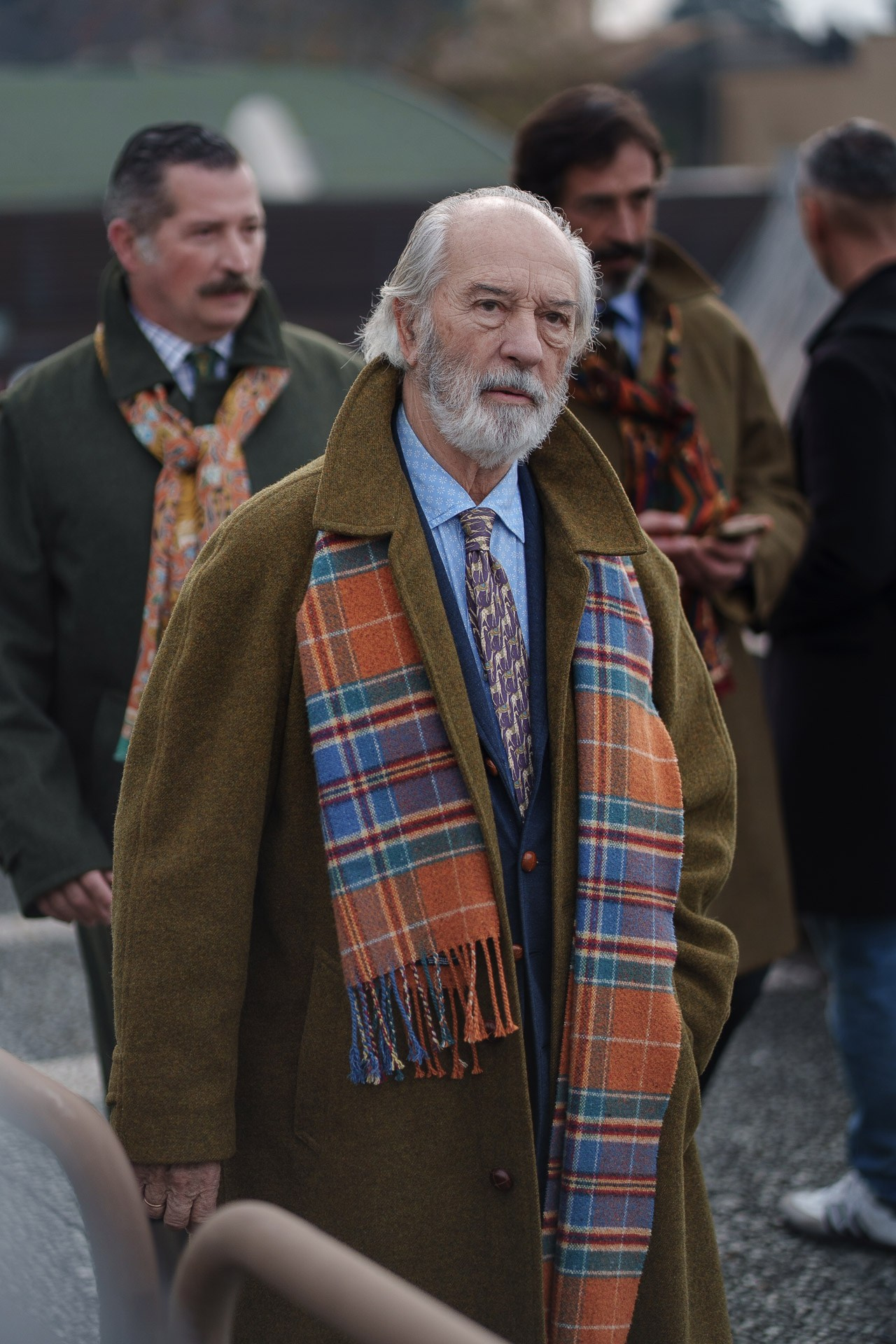 Older man in green coat and colorful scarf at Pitti Uomo 109 Florence