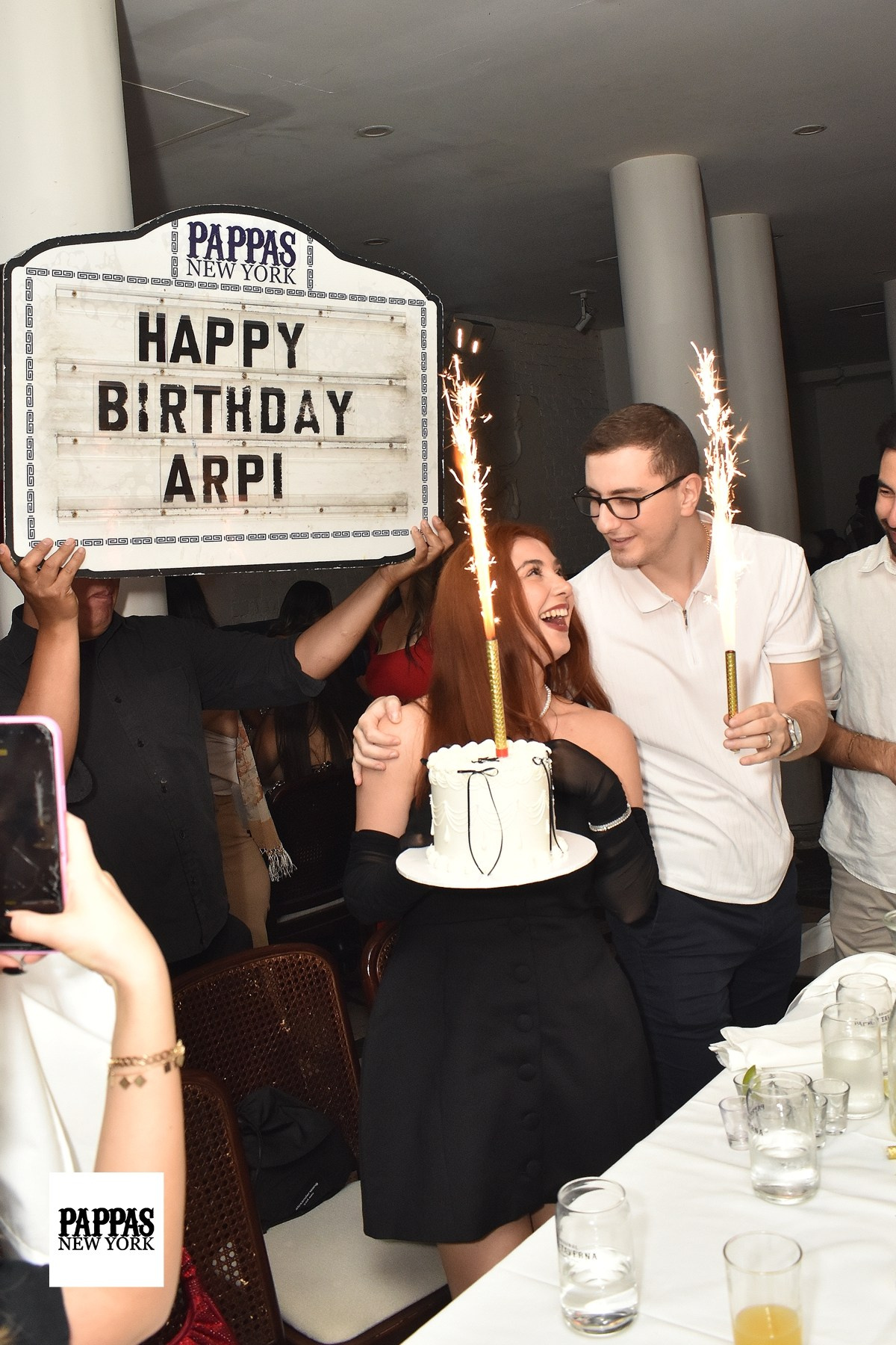 Guests celebrating at a birthday dinner with a “Happy Birthday” sign, restaurant event photos in NYC.