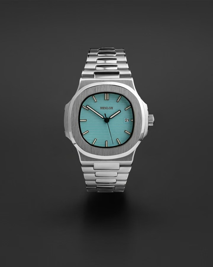 Stainless steel wristwatch with a turquoise dial on a dark studio background