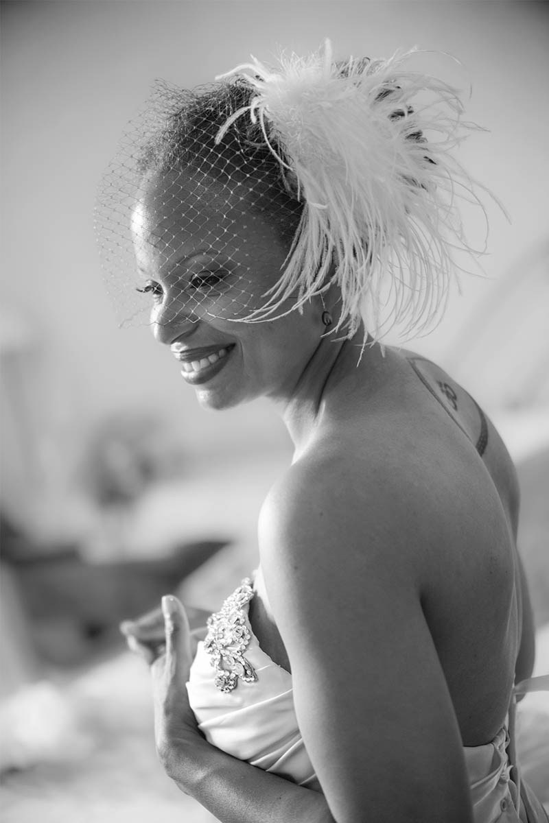 Smiling bride waits patiently in her suite at the Chateau Mcely as her wedding dress is laced up.
