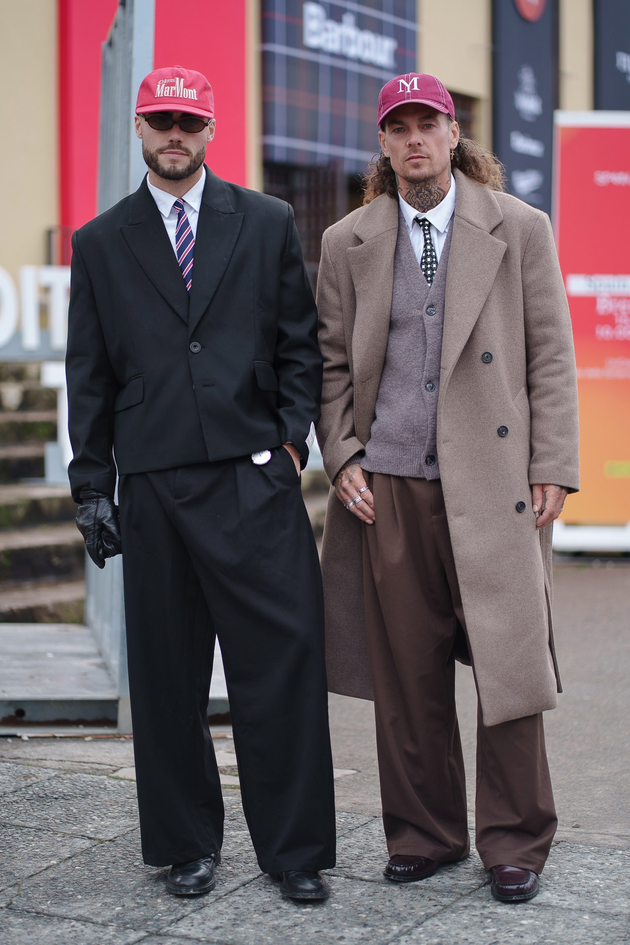 Two men in tailored coats and red caps posing at Pitti Uomo 109 Florence