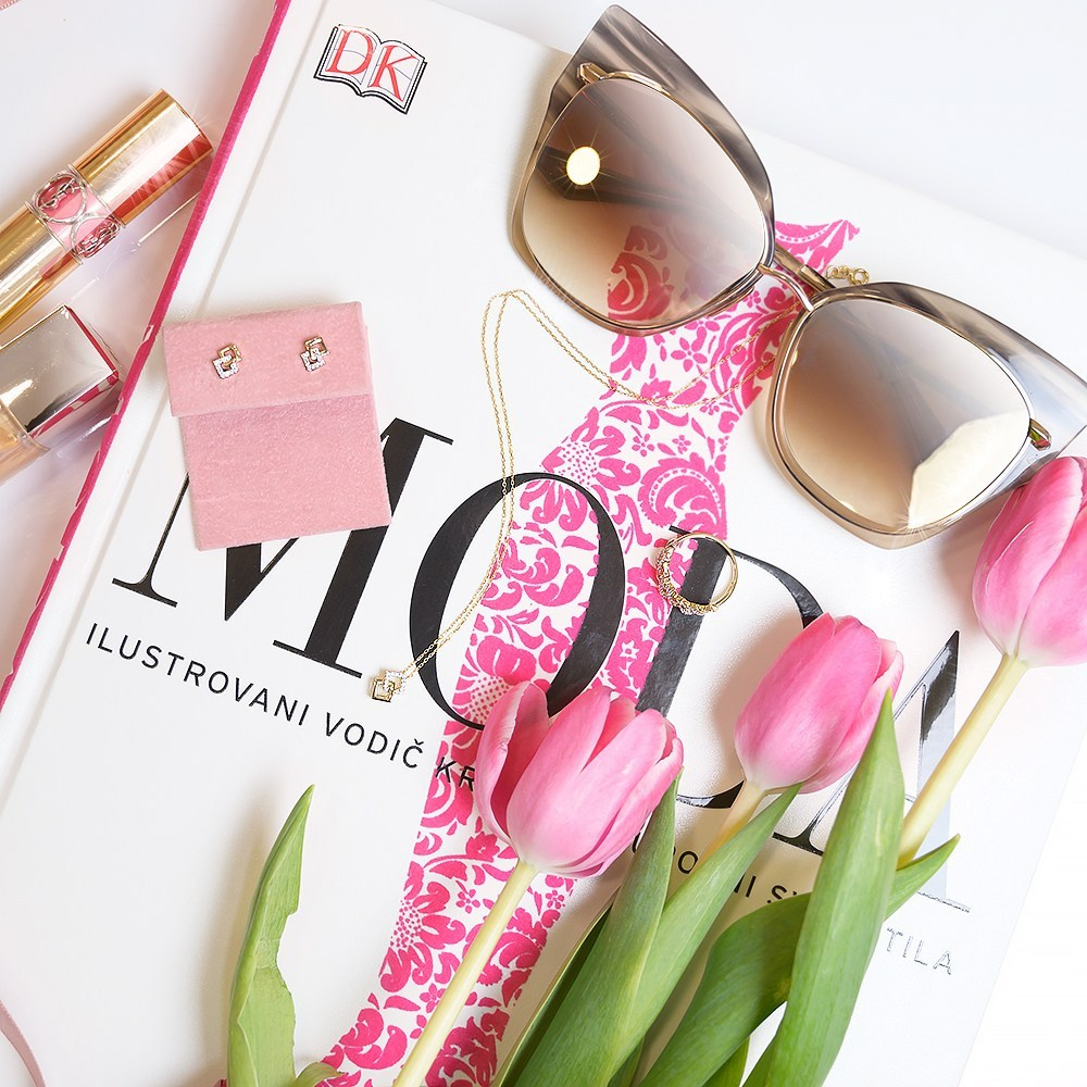 Zlatni nakit na modnom časopisu sa cvećem i naočarima za sunce.