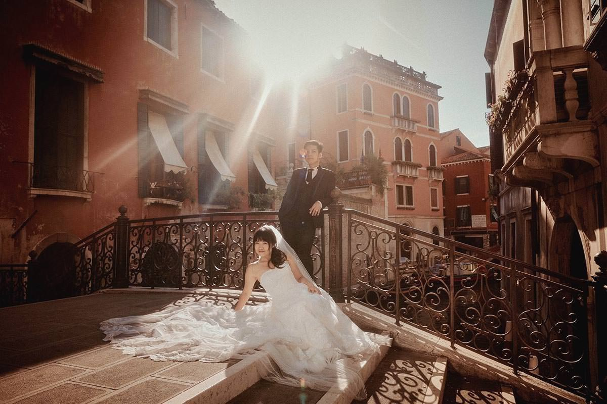 Daisy and Luis pause for a portrait as the sun flares vividly around them above a canal in Venice.