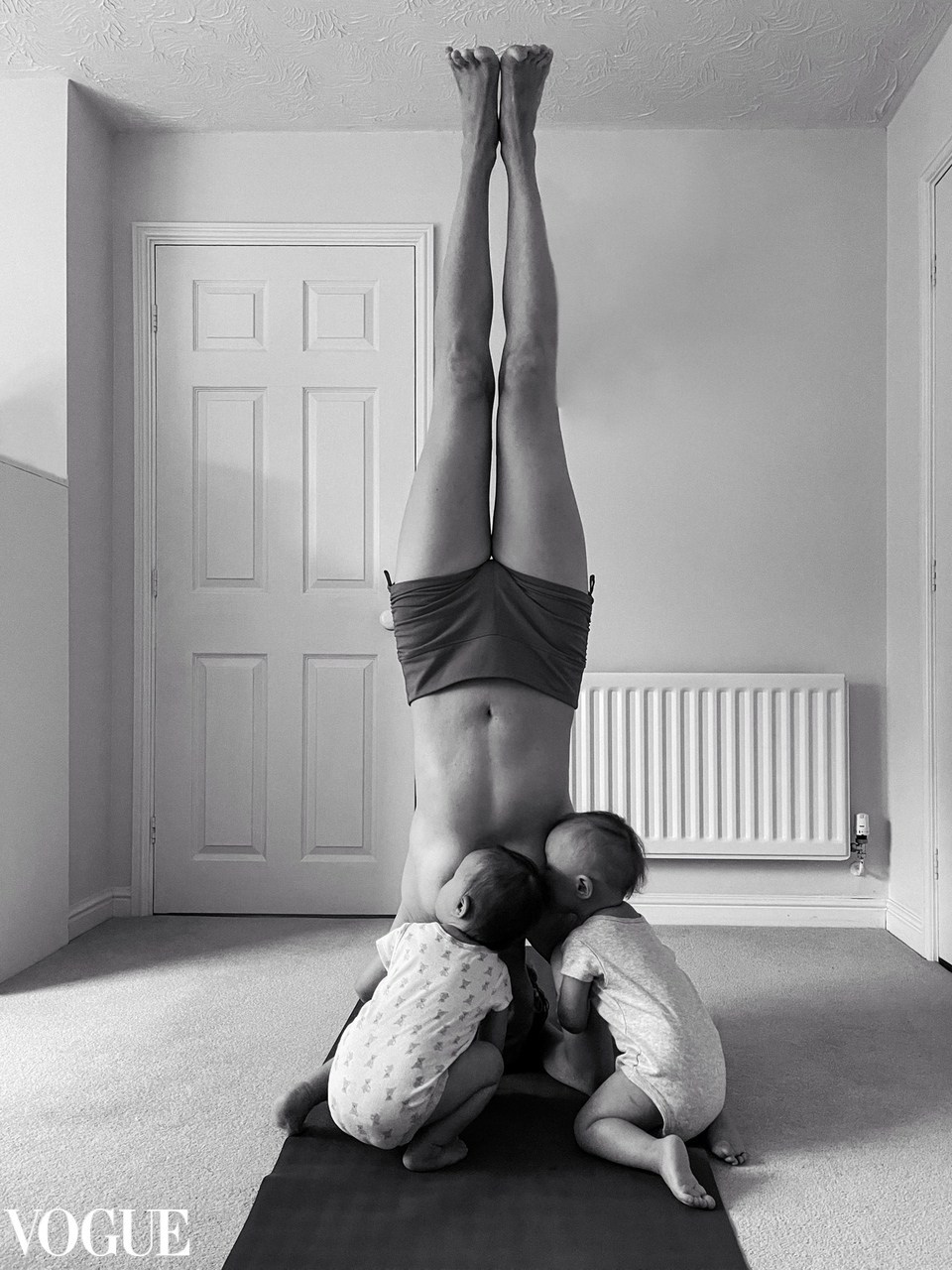 Black and white fine art portrait of a mother breastfeeding twins while doing a headstand, powerful and playful family photography in Solihull.