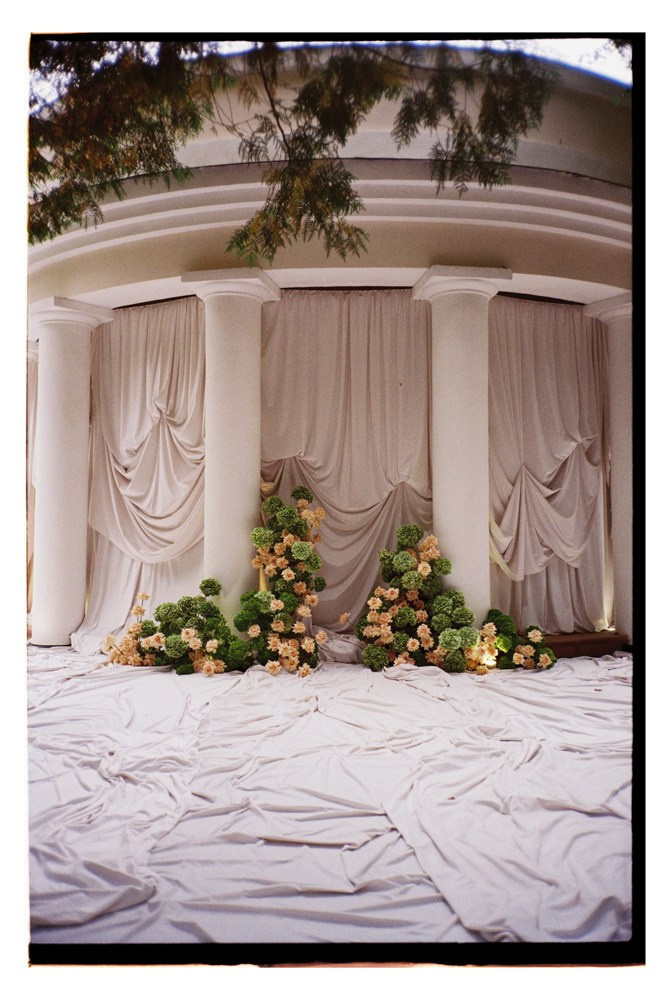 Draped ceremony backdrop with florals during luxury wedding setup