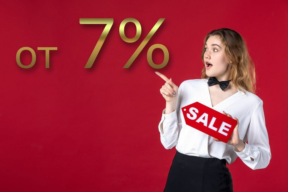 Молодая девушка с баннером "Скидка" в руках указывает на 7 процентную выгоду.