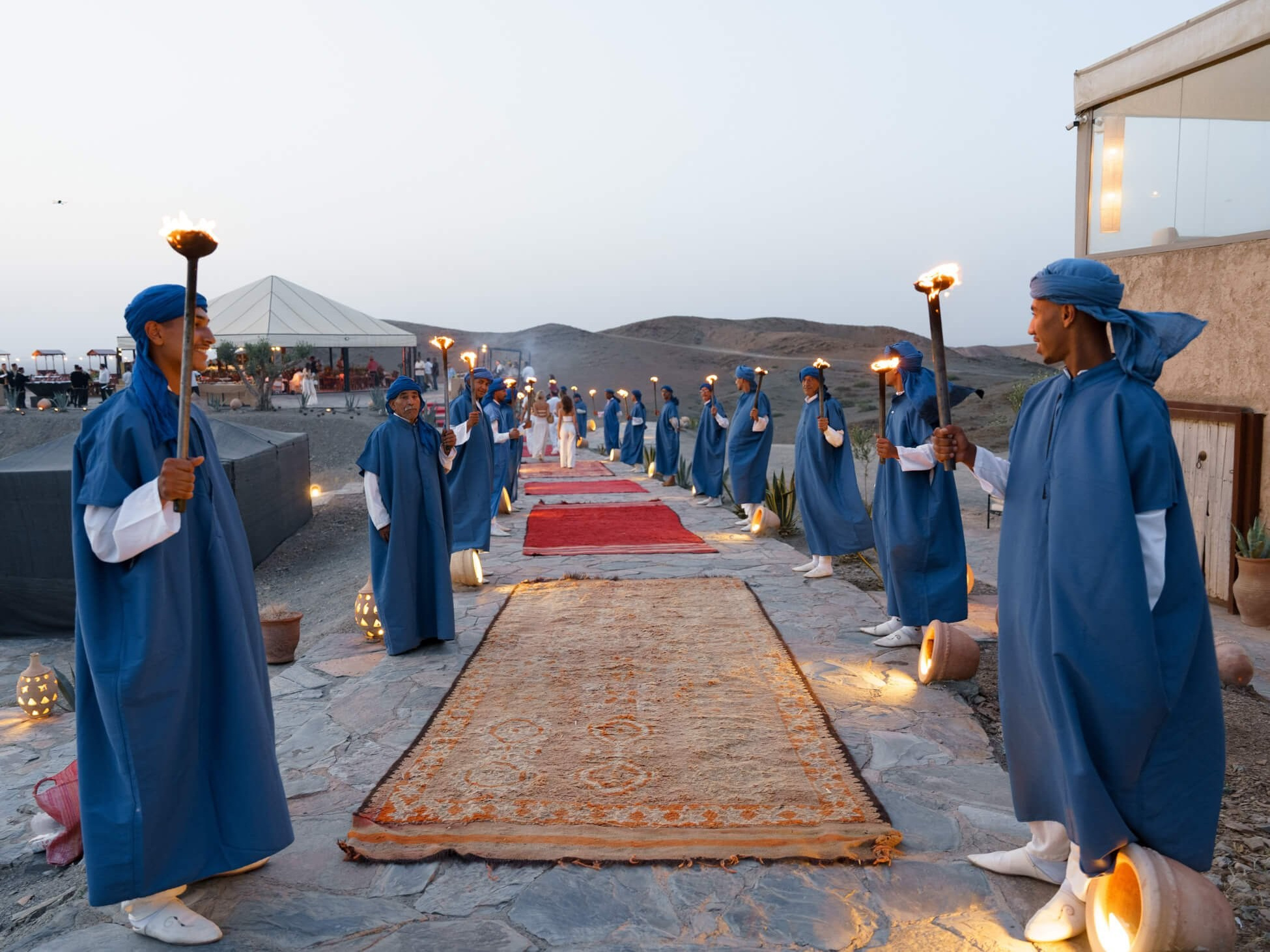 Torchbearers lining carpet path for luxury desert wedding entrance, Morocco