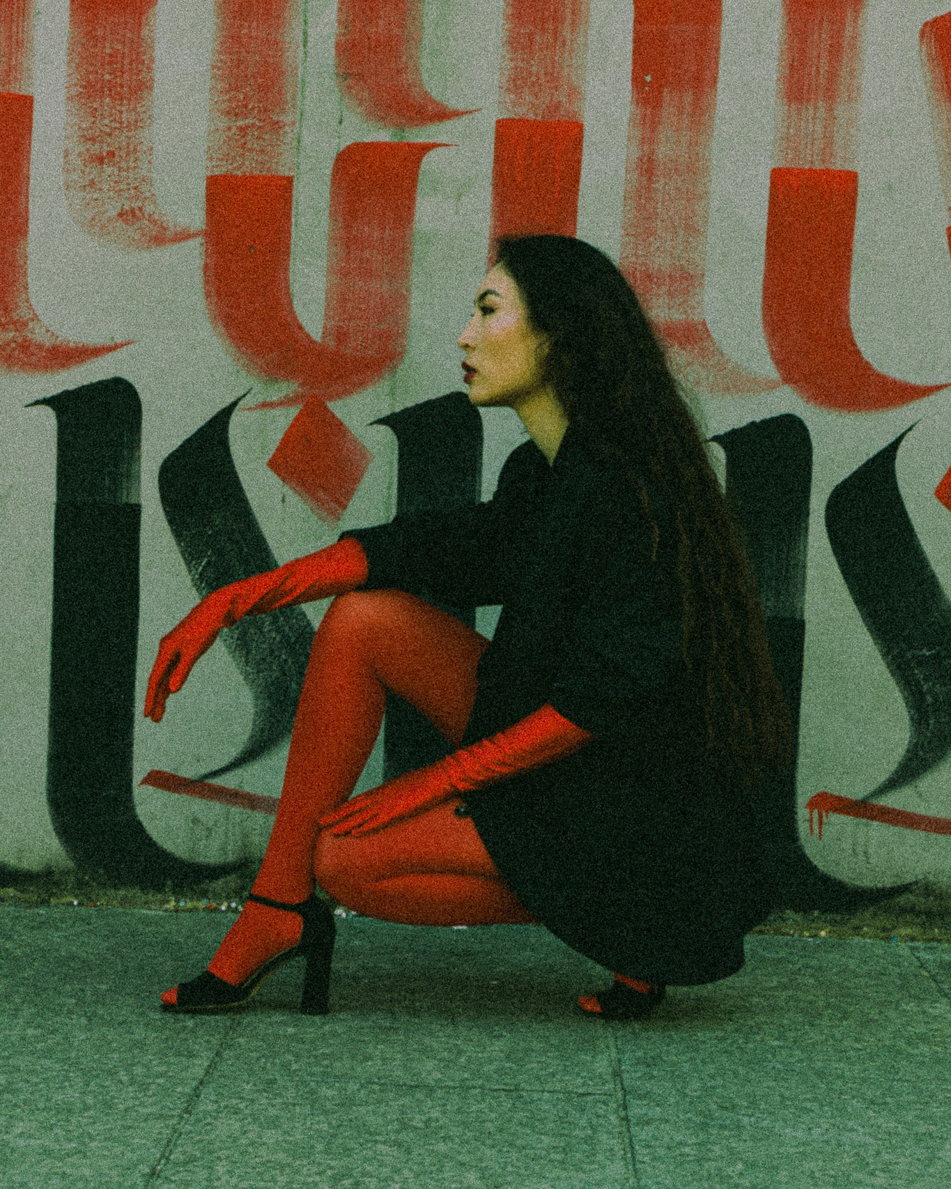 Woman in red gloves and tights posing against colorful graffiti wall in Milan