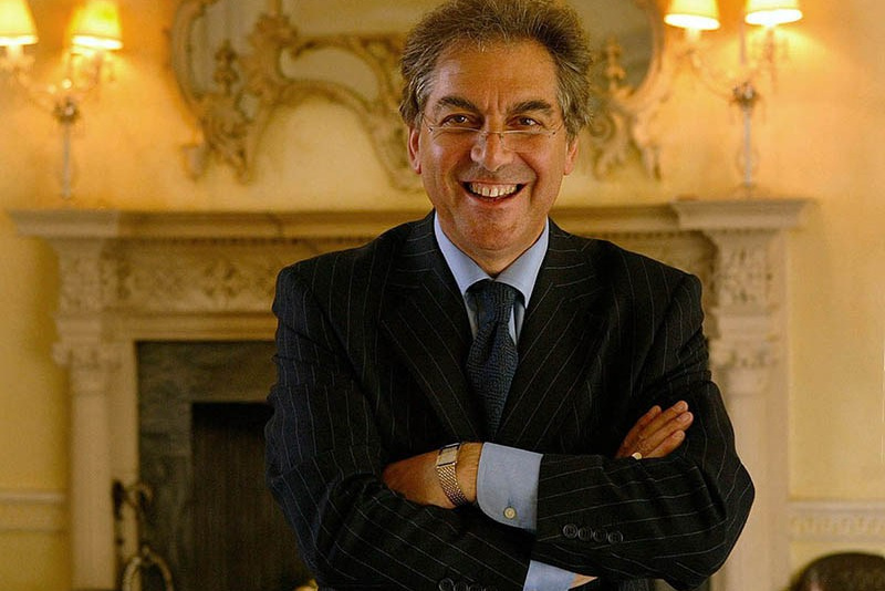 Editorial image of a cowboy silhouetted against the rays of sunlight that are breaking in a stockyard as he herds cattle.