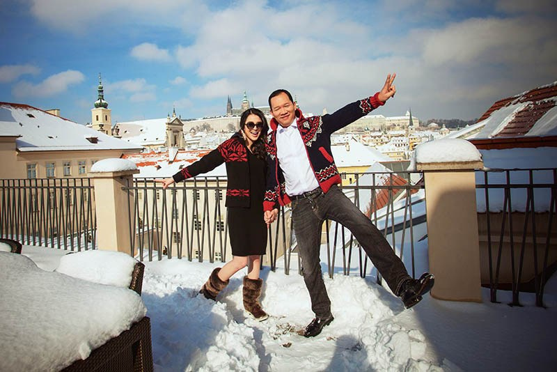 The stylish Hong Kong couple pose on the Mandarin Oriental Presidential Suite terrace overlooking winter Prague.