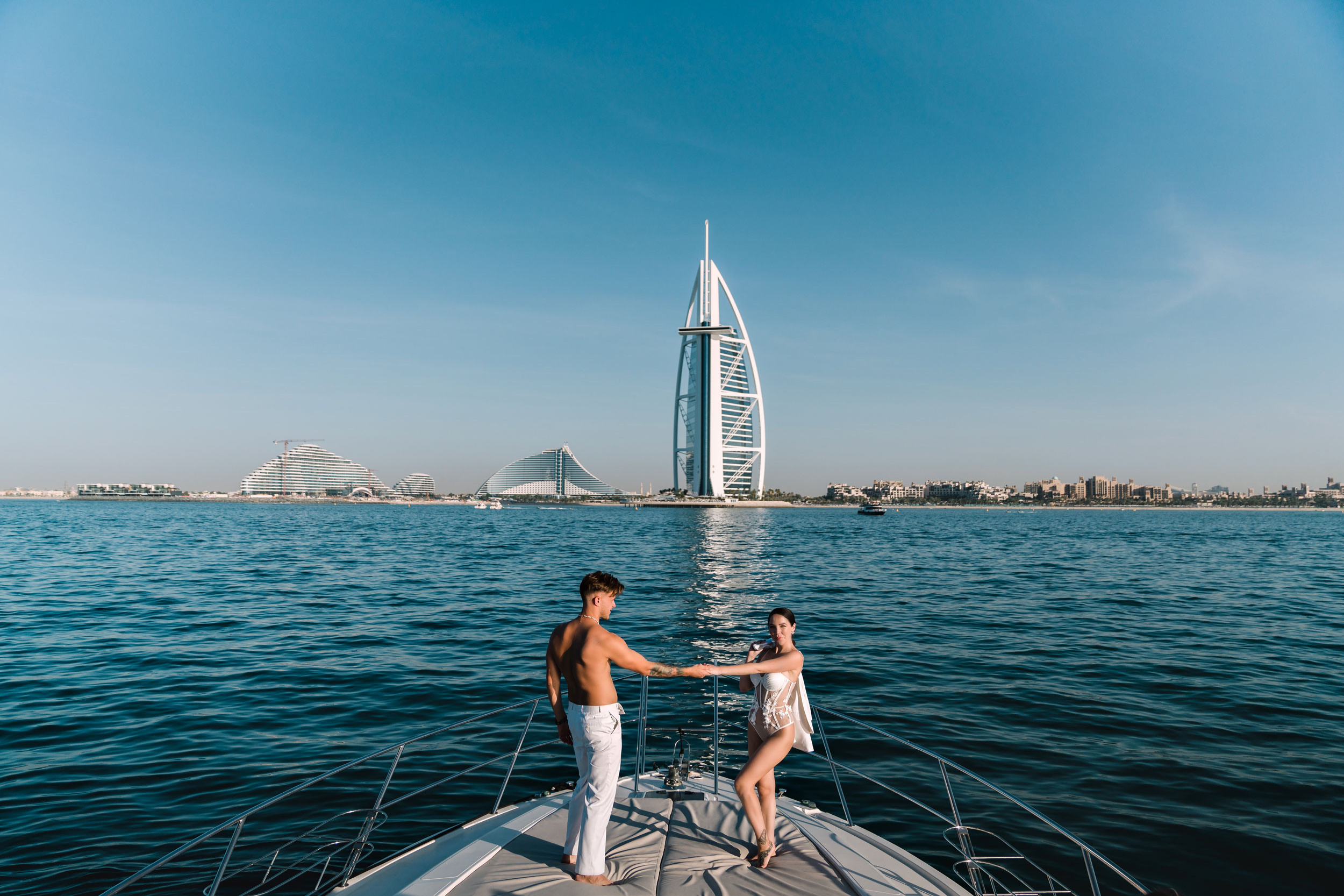 stylish lady in bikini and her boyfriend are dancing on a yacht