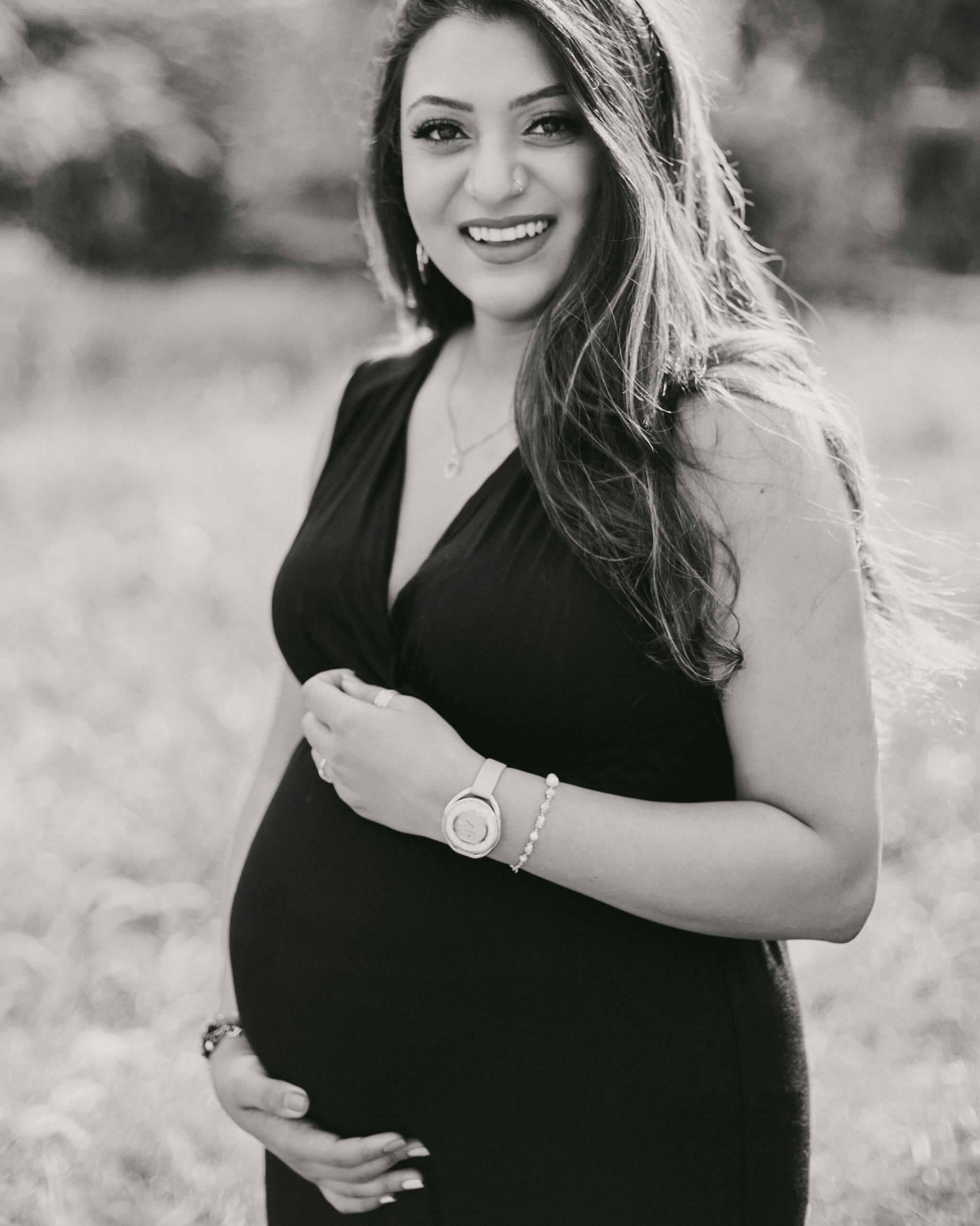Kenya maternity photography in classic black & white — woman holding her baby bump under a flowering tree.