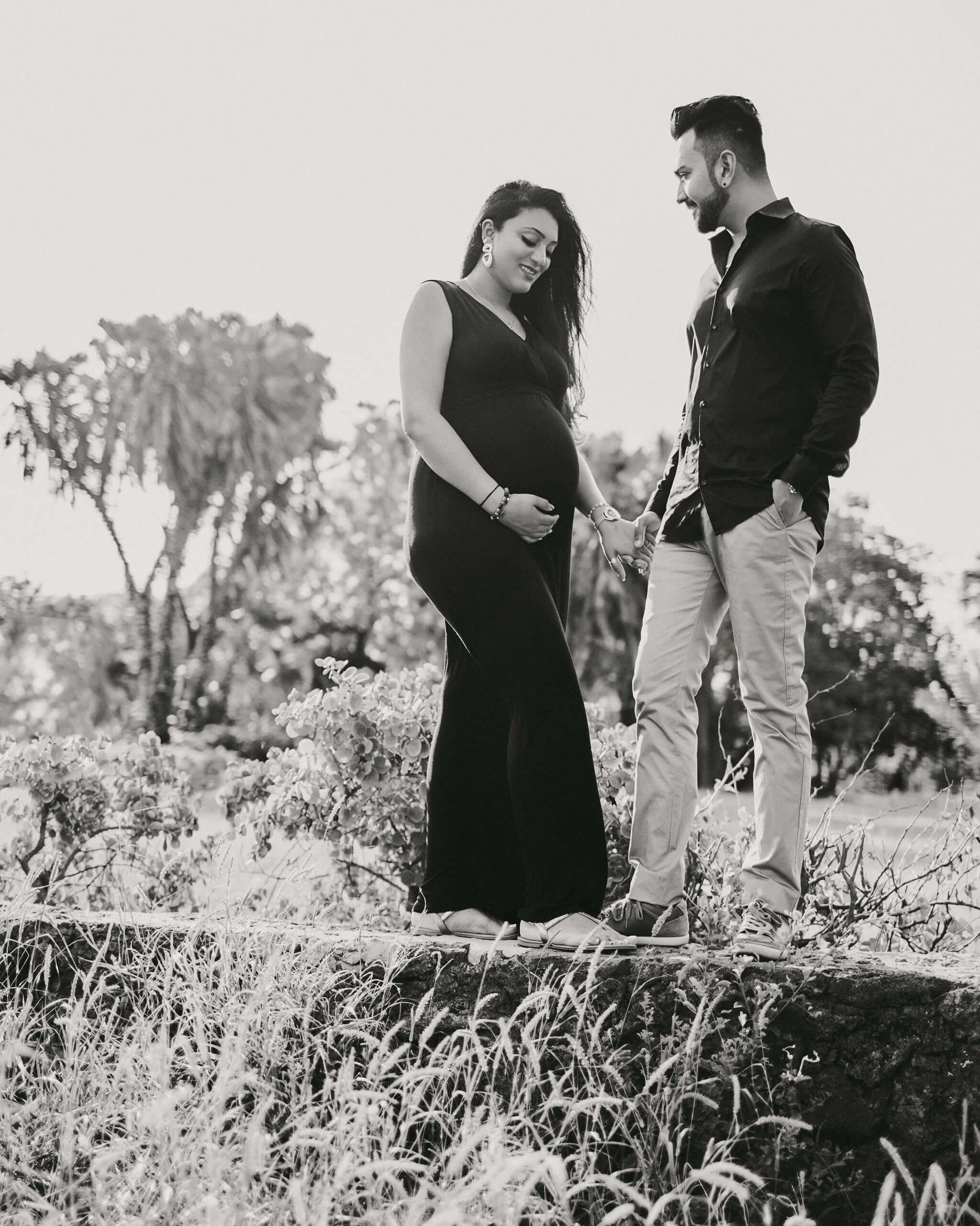 Timeless couple maternity portrait by Kenya beach garden, dressed in vintage-inspired outfits.