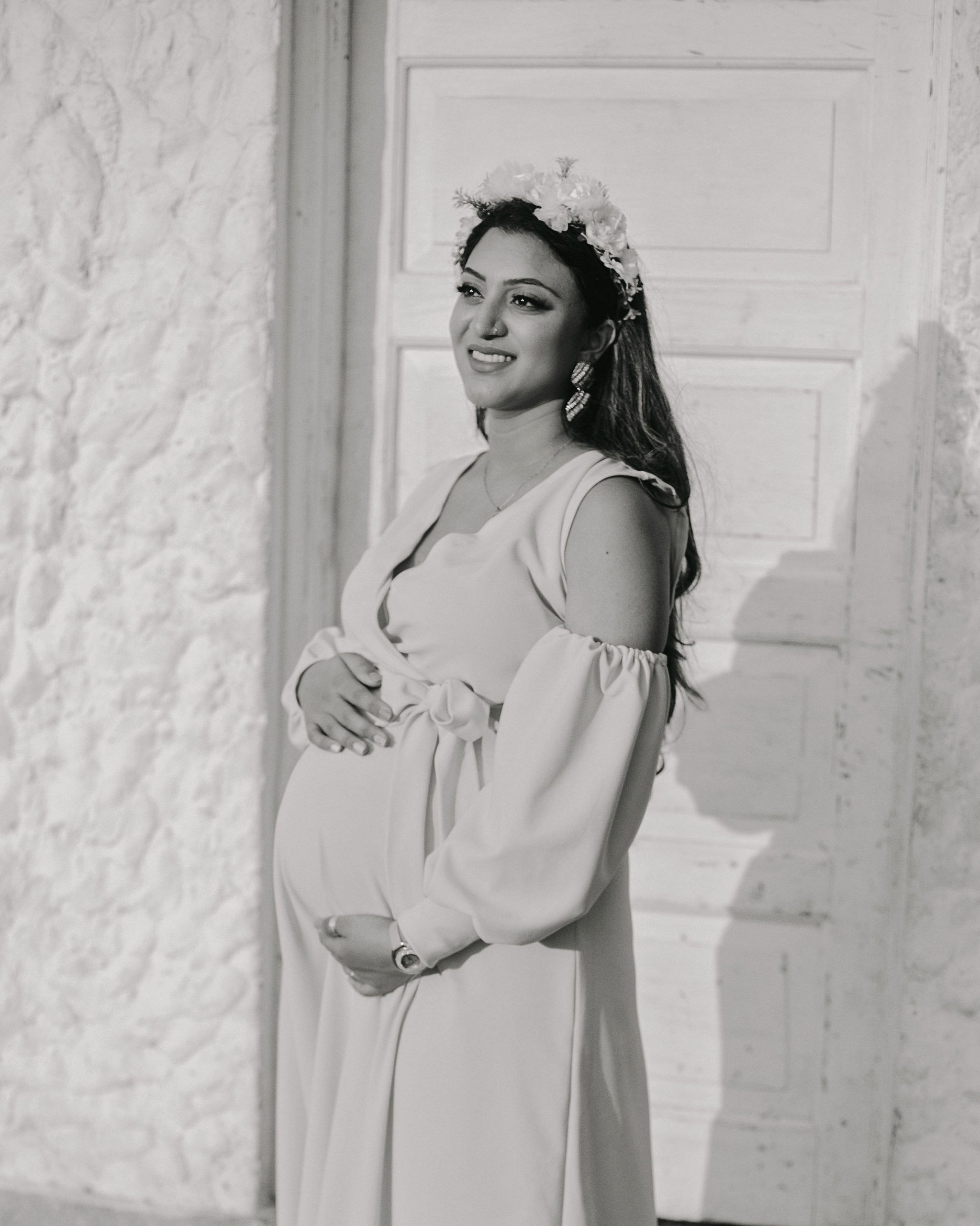 Mombasa Maternity photoshoot in black and white — glowing mother with relaxed expression by villa wall.