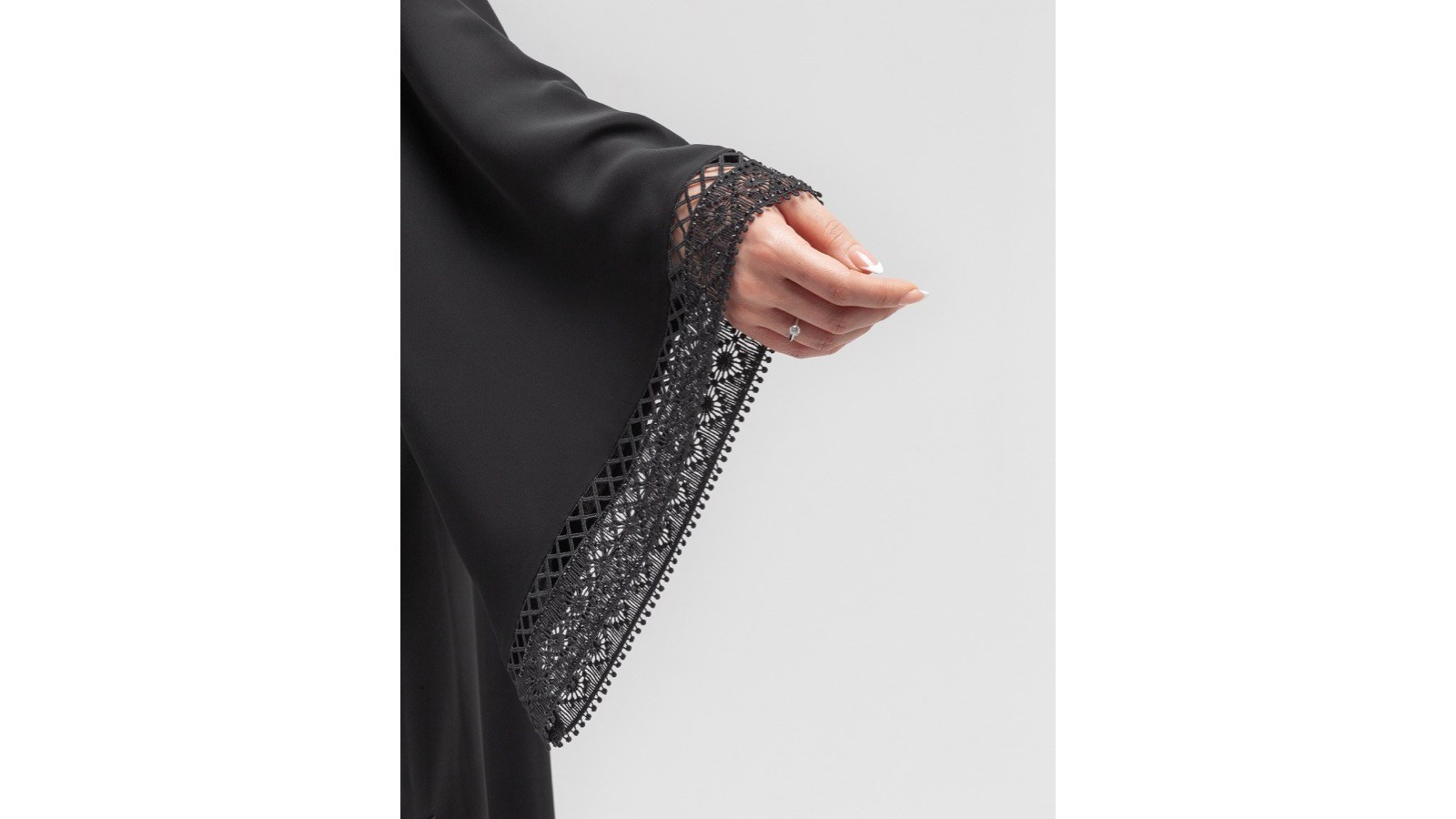 Black abaya sleeve and lace detail photographed on a clean white background in the UAE