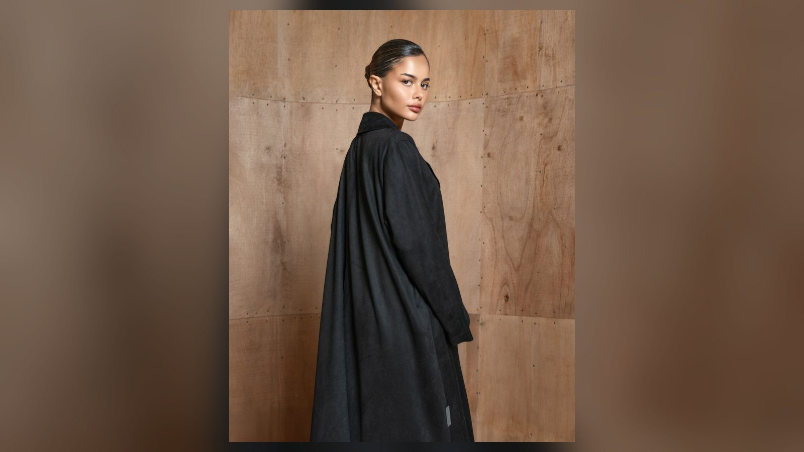 Black abaya photographed on location against warm architectural textures in the UAE
