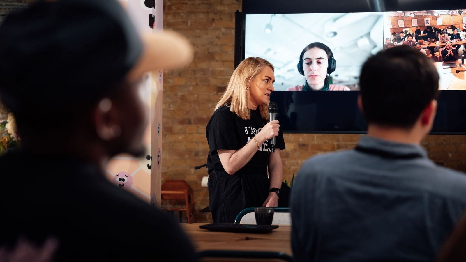 Presenter addressing an in-person audience while a remote participant joins a hybrid corporate event