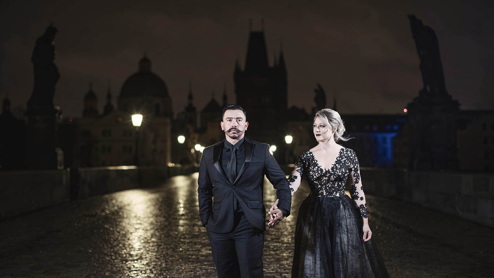 Couple in black dancing standing on Charles Bridge all alone at night