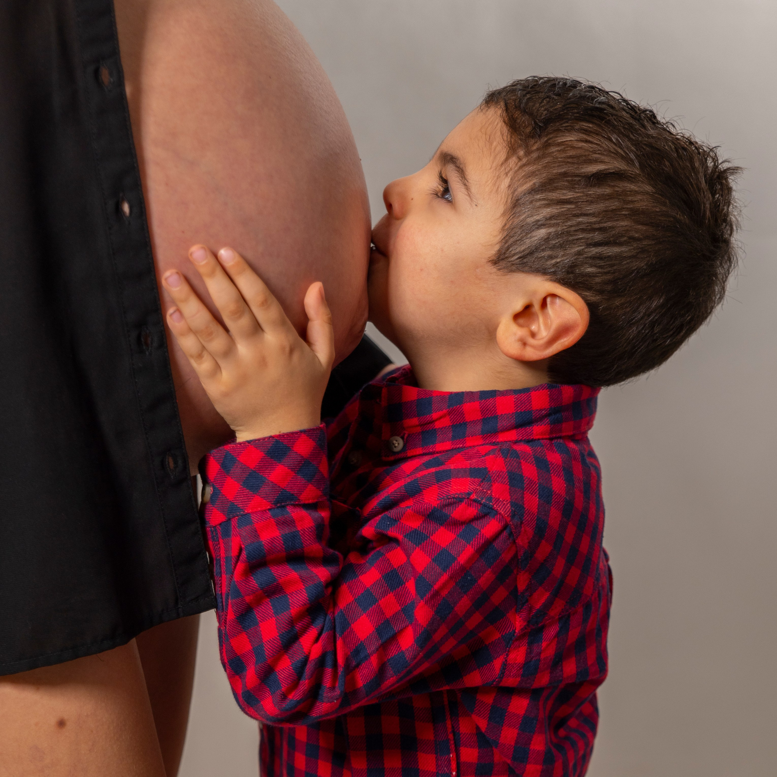 foto de barriga de embarazada y su hijo pequeño besandola