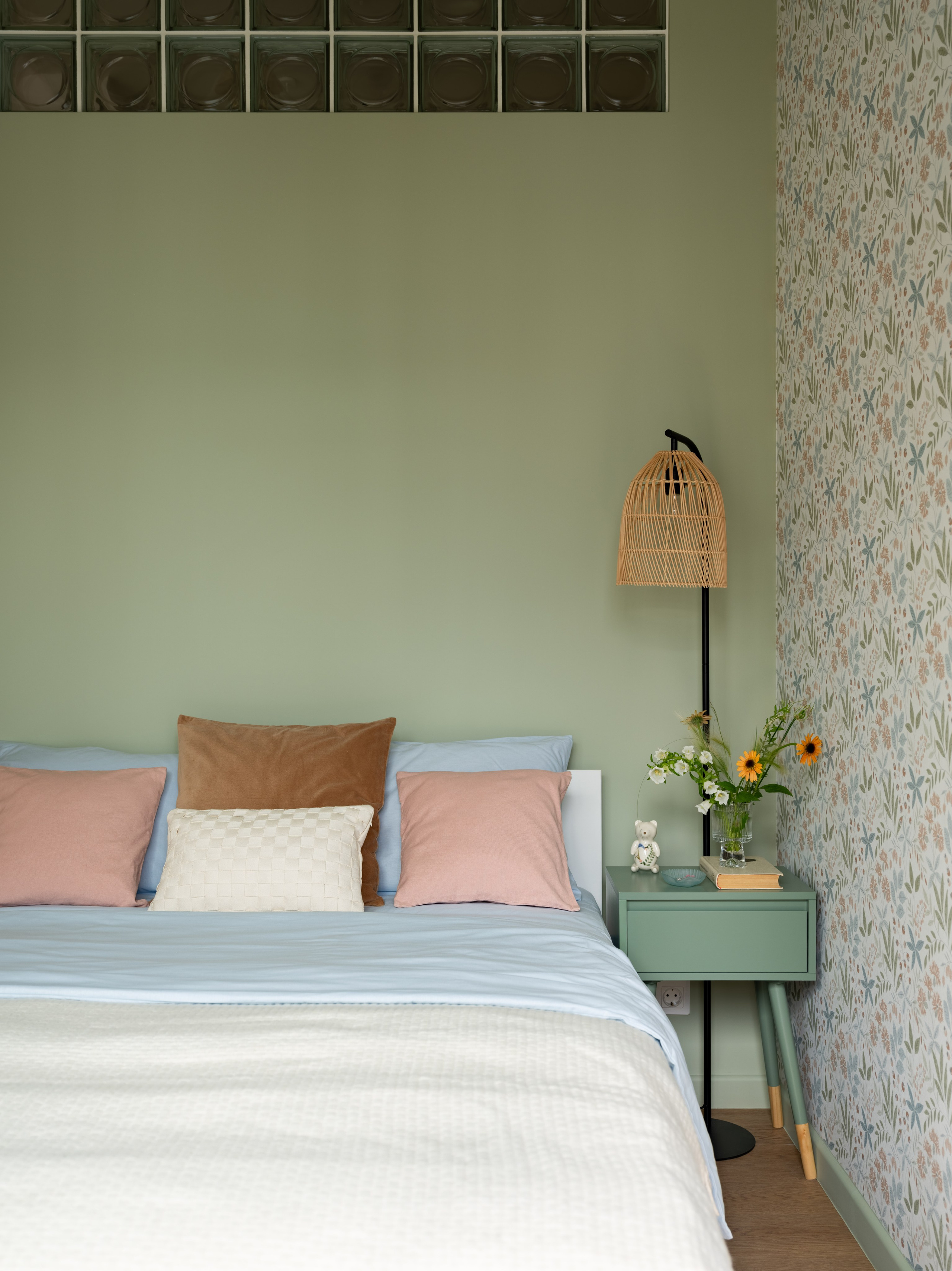 Кровать с подушками и цветочными обоями в интерьере маленькой студии