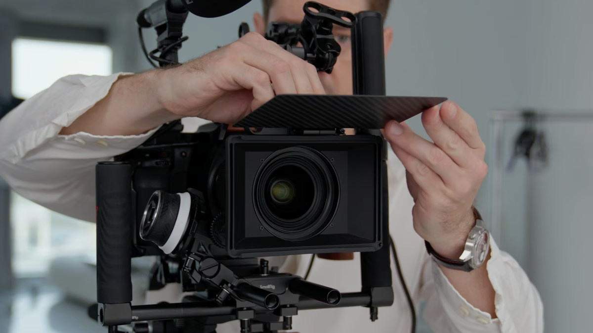 Camera operator preparing a professional cinema camera for a business video podcast recording