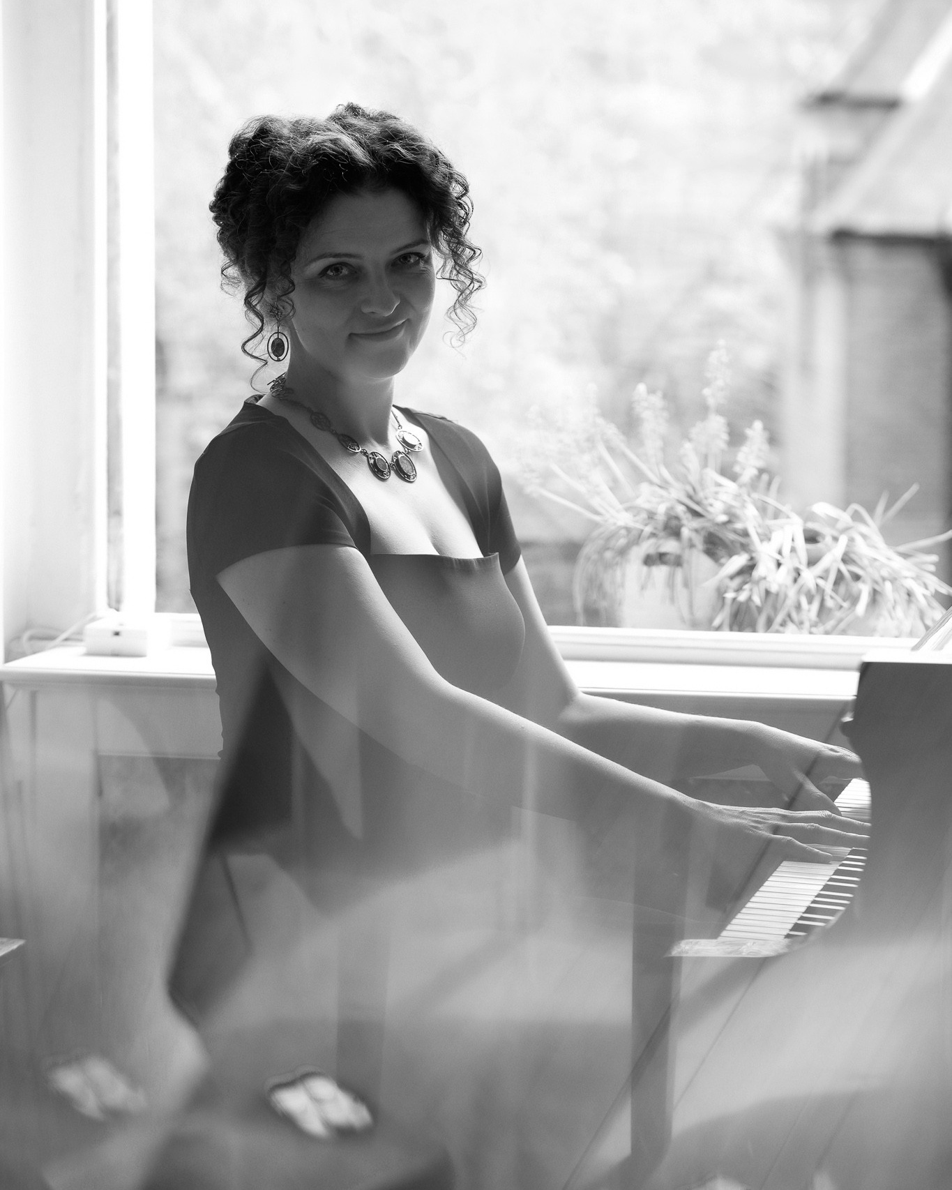 A lady playing the piano with curly hair. Individual artistic photoshoot. 