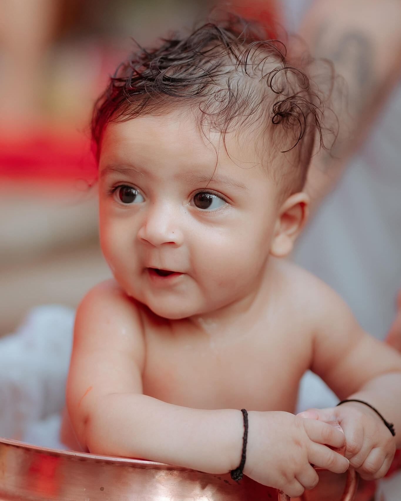Smiling baby enjoying a milk bath in a copper vessel on the day of Pasni in Butwal