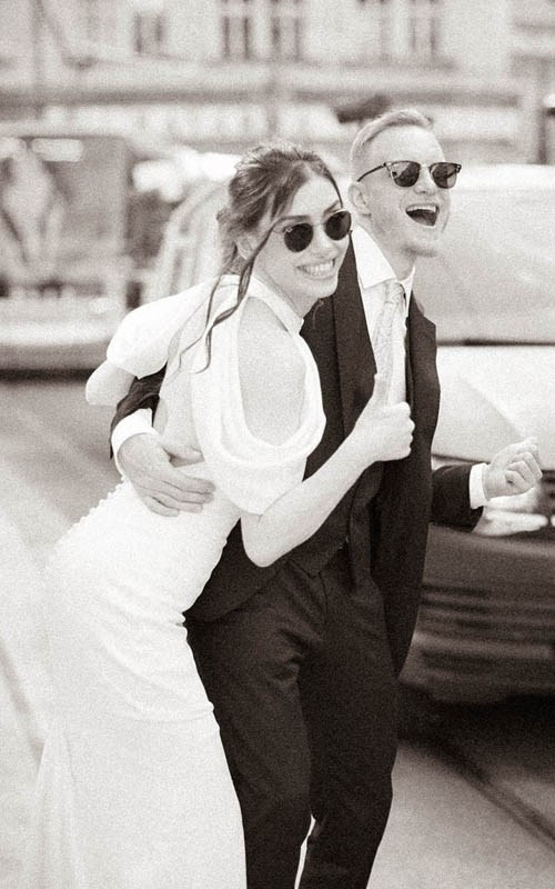 A stylish Turkish and Czech mimic hitchihiking in front of the Masarykovo Train Station in Prague during their wedding day portraits   
