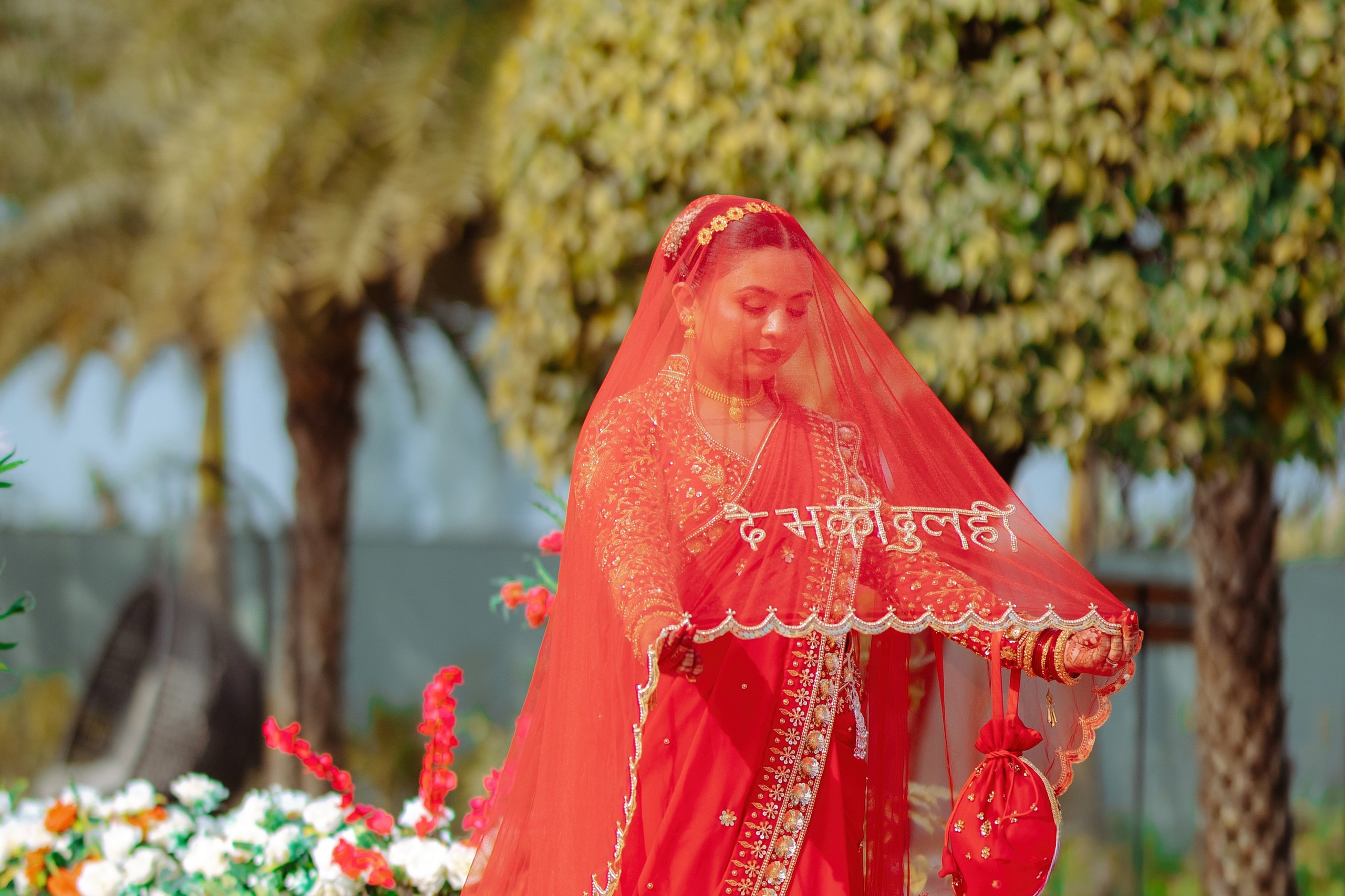 A beautiful Nepali bride wearing a traditional red saree and a 'Devaki Dulahi' embroidered veil, captured by Poudel Digital Photography.